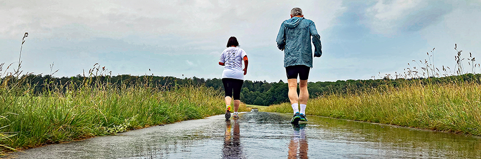 Paar beim Joggen auf verregneten Straßen