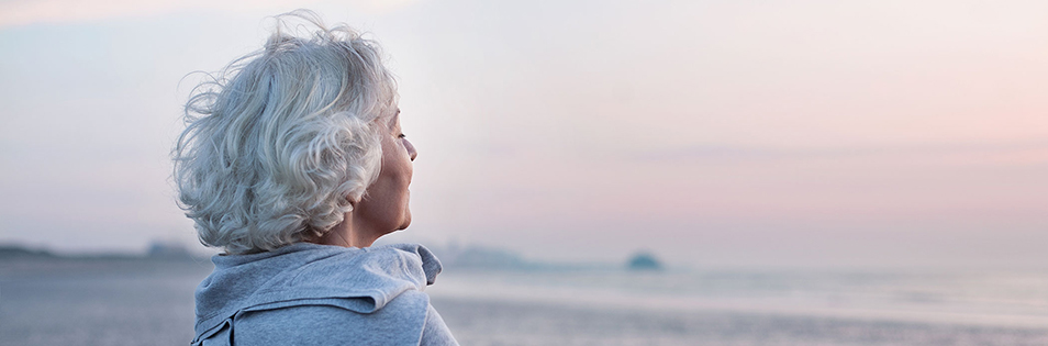 Person blickt am Meer in die Ferne.