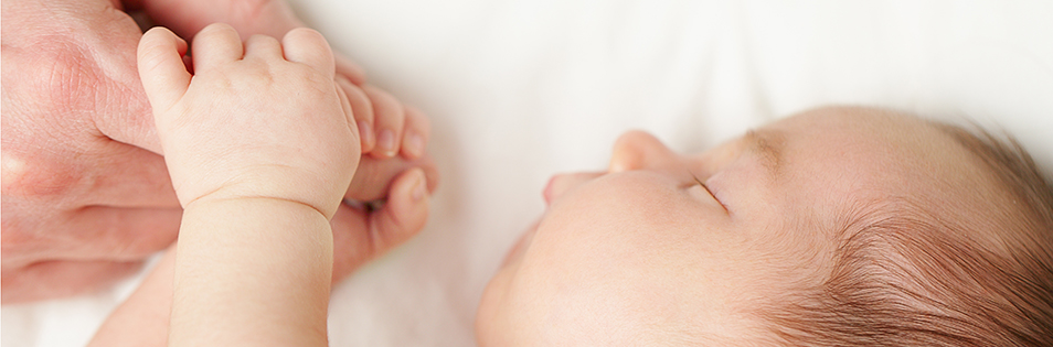 Schlafendes Baby umklammert den Finger der Mutter