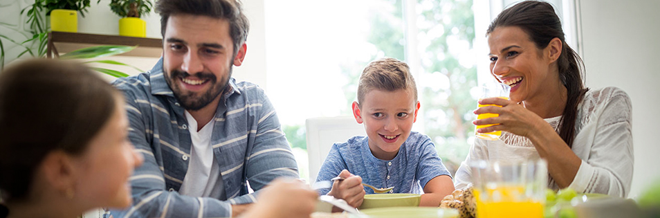 Mehrere Personen sitzen gemeinsam an einem Esstisch und essen eine Mahlzeit.