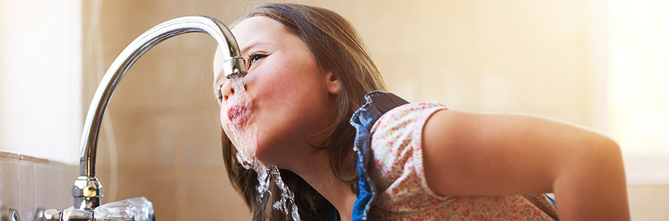 Kind trinkt Wasser direkt aus dem Wasserhahn