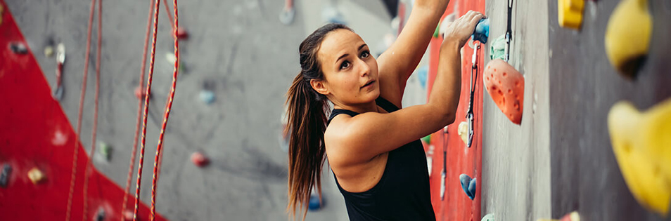 Person beim Klettern an einer Indoor-Kletterwand im Rahmen eines therapeutischen oder sportlichen Trainings.