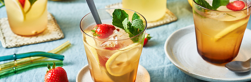 Gesunder Durststiller im Glas mit Zitrone, Eiswürfel, Minze und Erdbeere