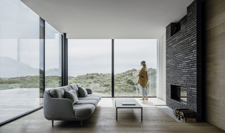 Modernes Wohnzimmer mit rahmenlosen Fenstern und Blick auf die Dünen – elegante Verbindung von Natur und Architektur