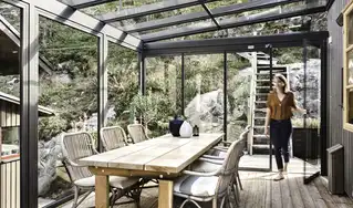 Frau verlässt verglaste Terrassenüberdachung in München mit Holzterrasse