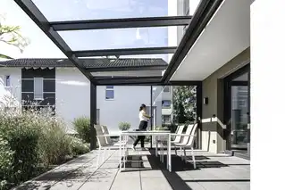 Terrassenüberdachung in München mit weißem Esstisch-Set und Frau im Hintergrund