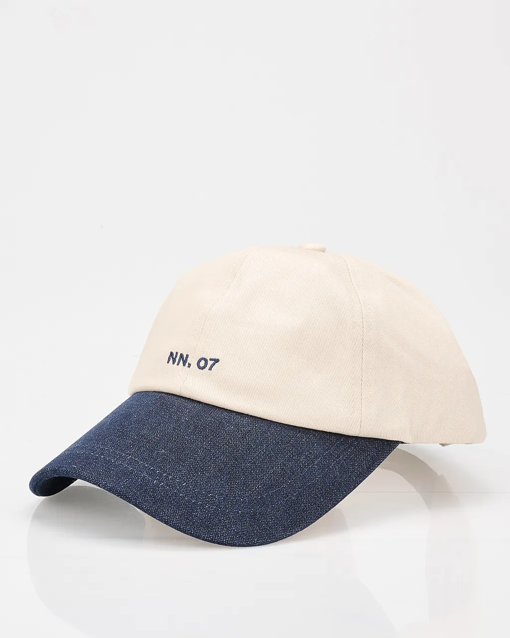 A beige baseball cap with a navy denim brim, embroidered with "NN, 07" on the front.