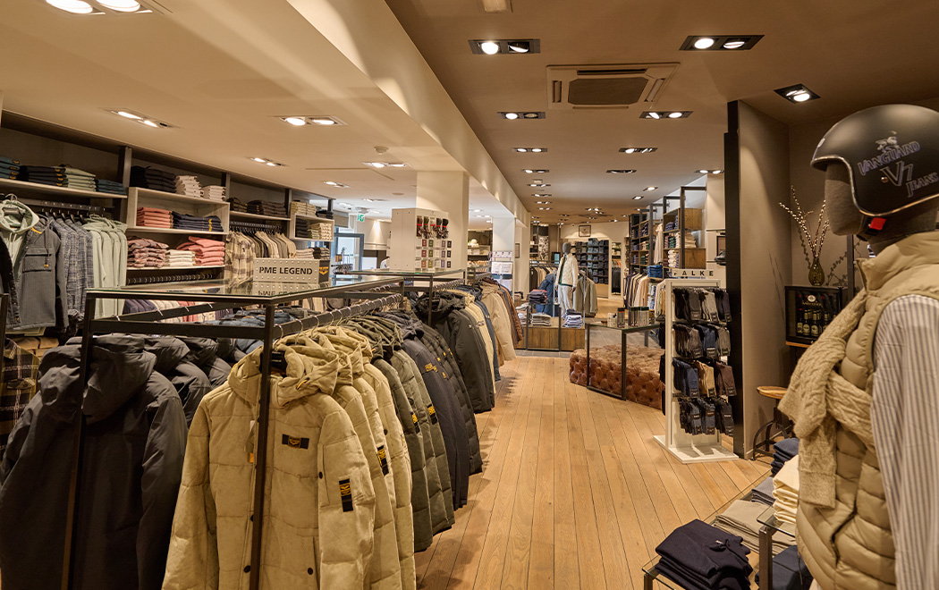 Overzicht van binnenkant OFM. Veldhoven. Verschillende kledingrekken met kleding