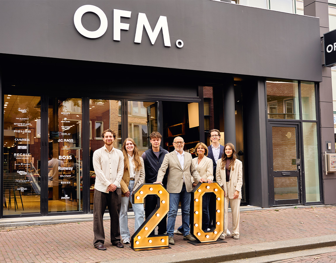 Personeel van OFM. Ede voor de winkel met grote lichtcijfers 20.