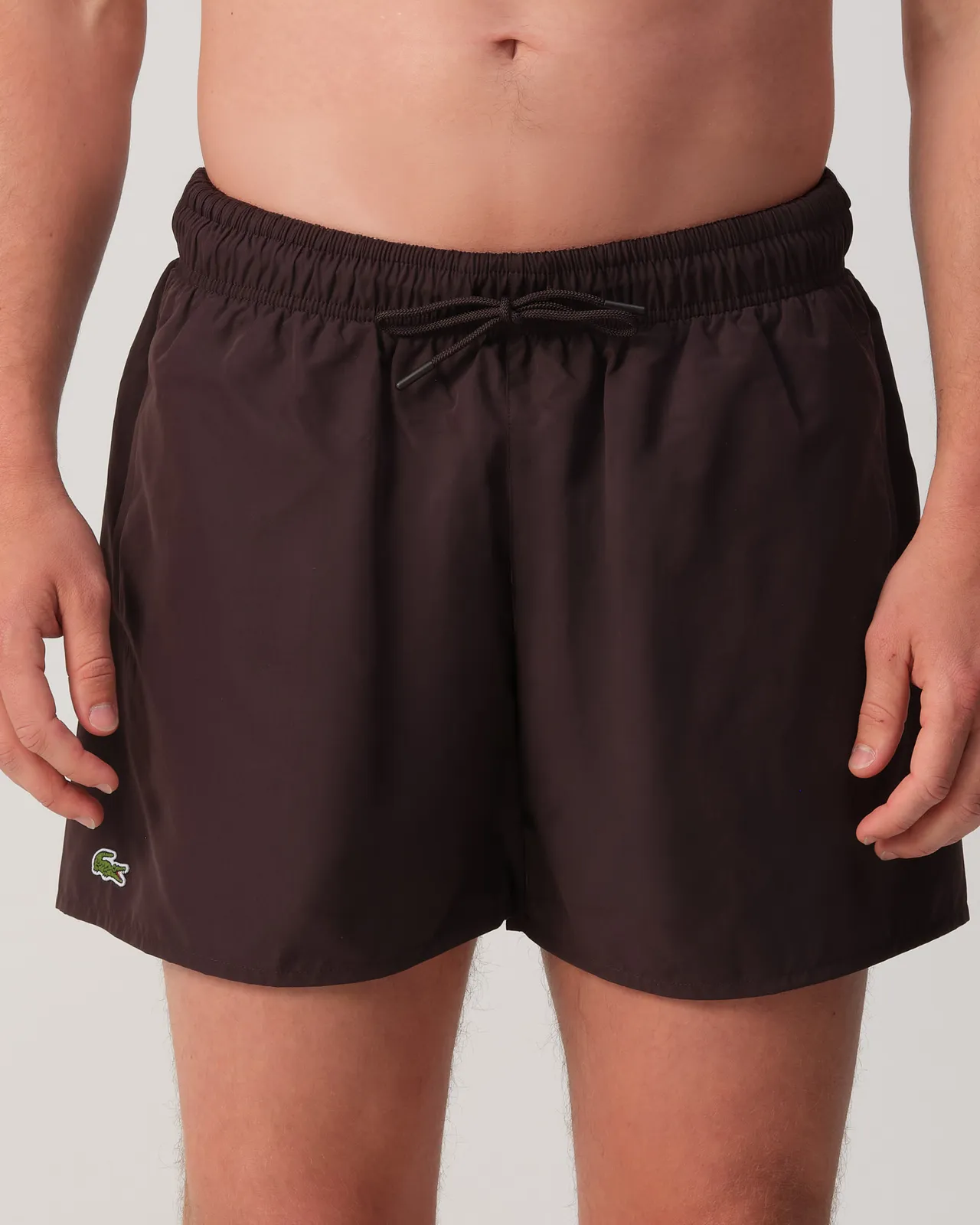 Man draag een bruine zwembroek van Lacoste