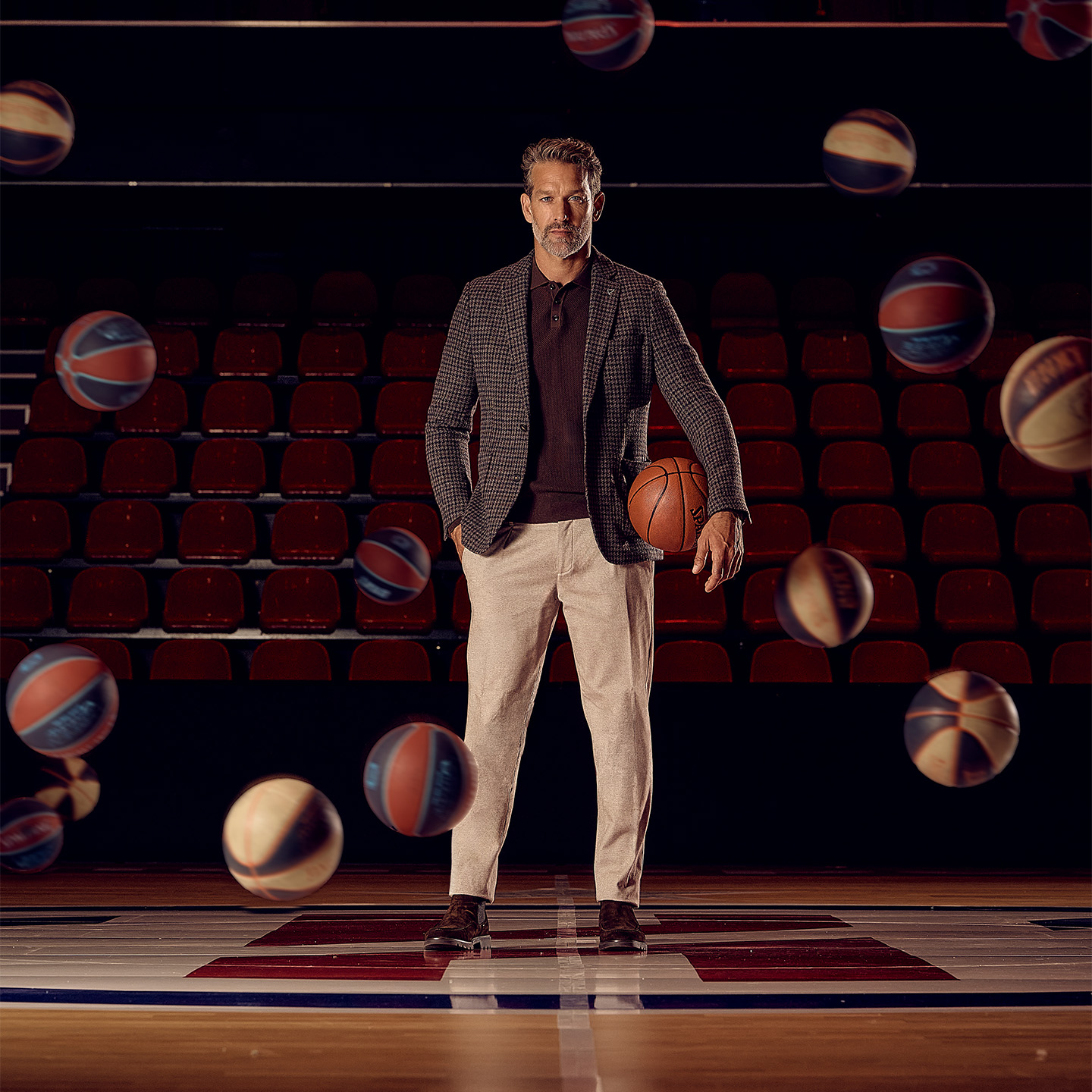 Model met najaarsoutfit, houdt basketbal vast. Rondom hem stuiteren ballen in de lucht