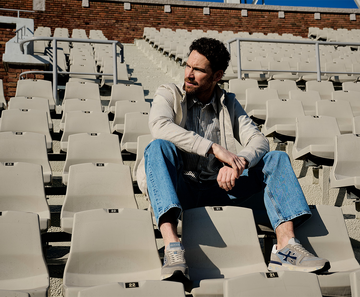 Model in Olympisch stadion in tribune, voorjaarsoutfit