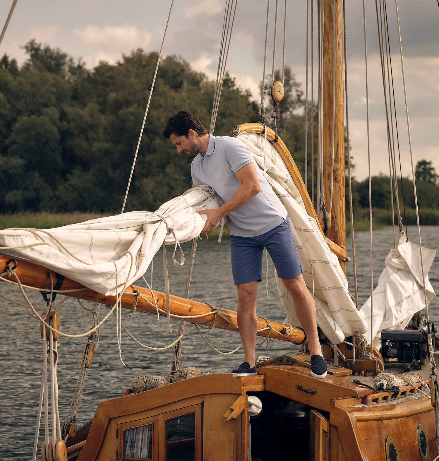 Man op een zeilboot leunend over de vlaggenmast