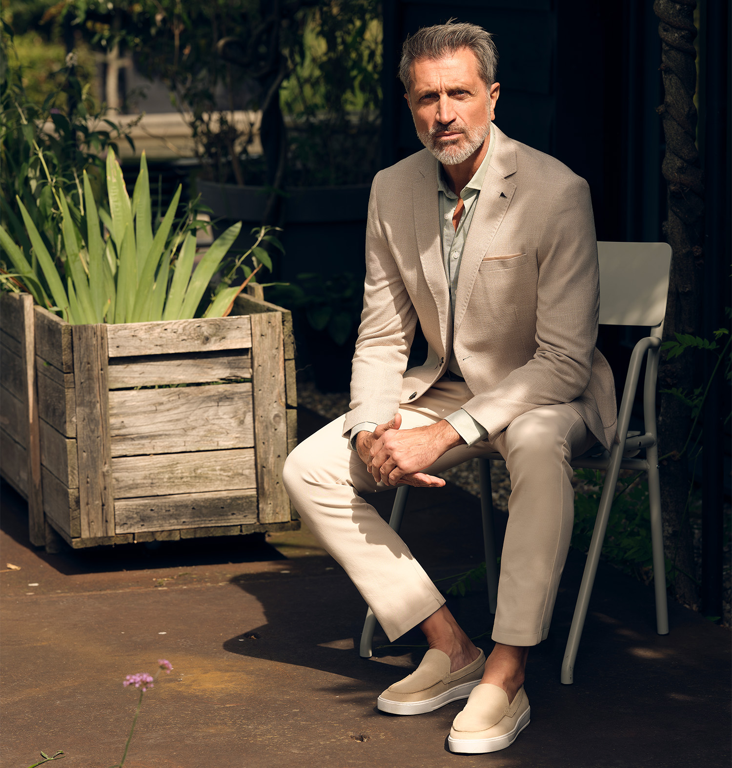 Man zittend in een beige pak op een stoel