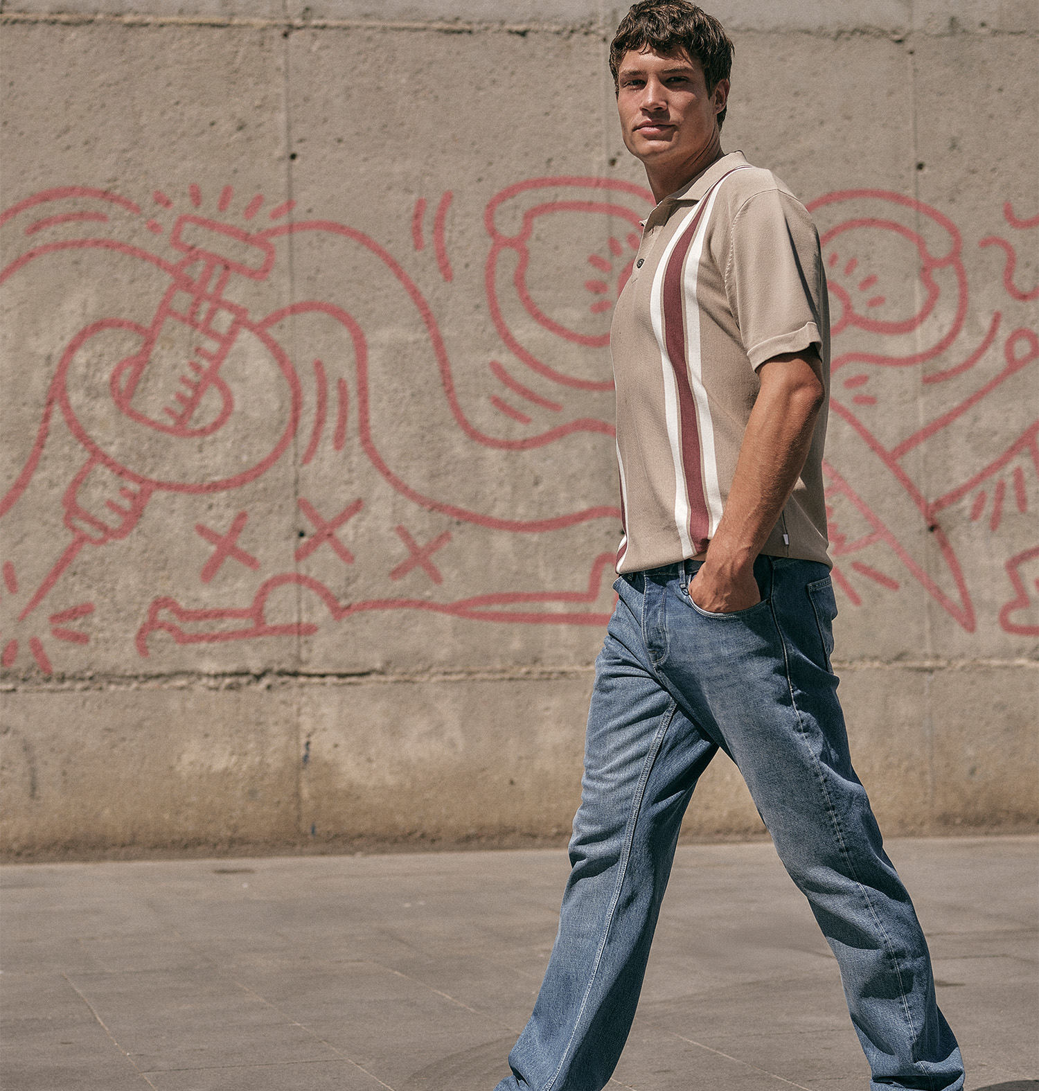 man lopend voor een met graffiti bespoten muur