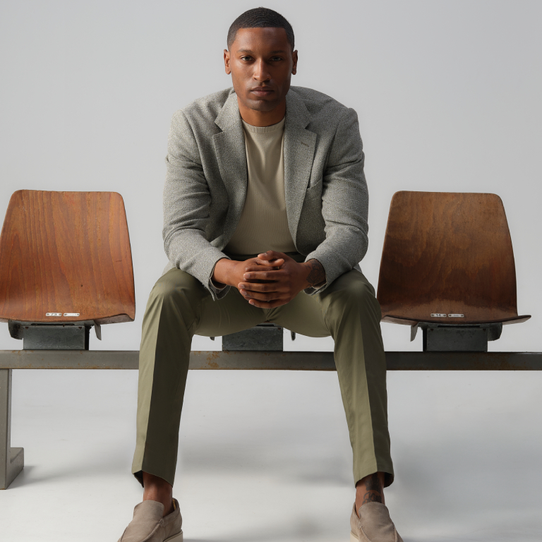 Man zittend op een stoel met een colbert en chino aan