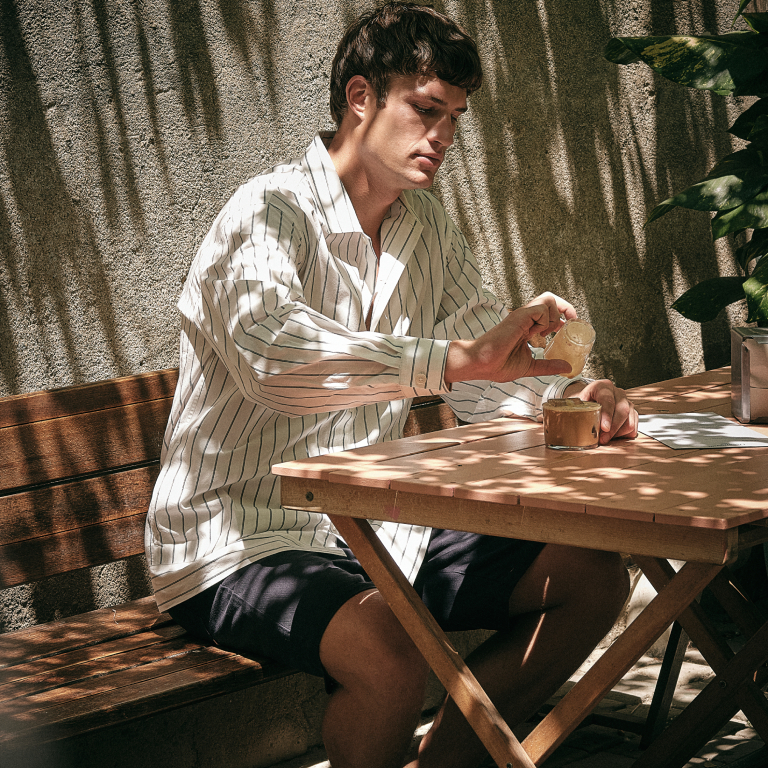 jongen zittend aan een tafel die koffie inschenkt