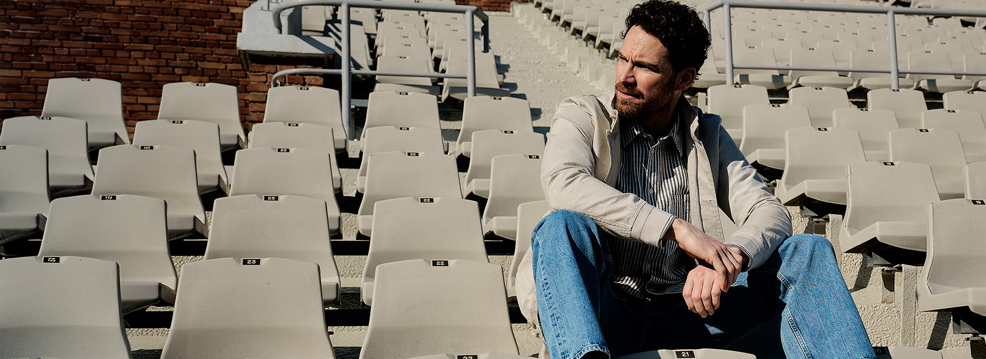 Model in Olympisch stadion in tribune, voorjaarsoutfit