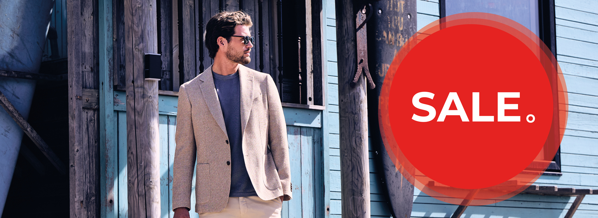 Man in a beige blazer stands outside a building, looking away. A large red circle with "SALE" text overlays the image.