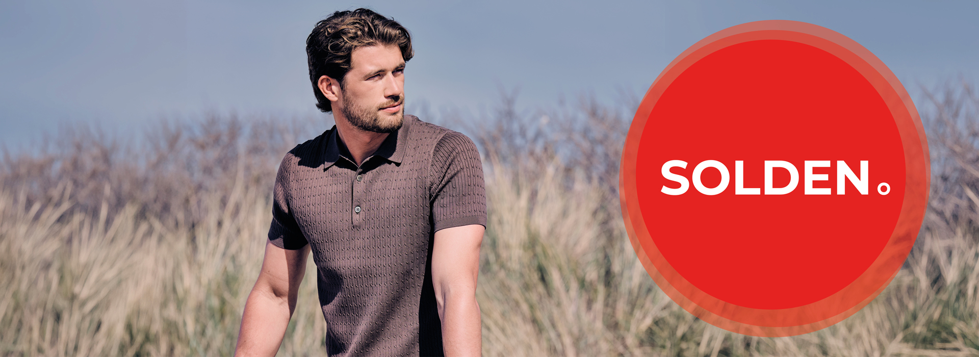 Man in a brown polo shirt stands outdoors with tall grass in the background. A large red circle with "SOLDEN" appears beside him.