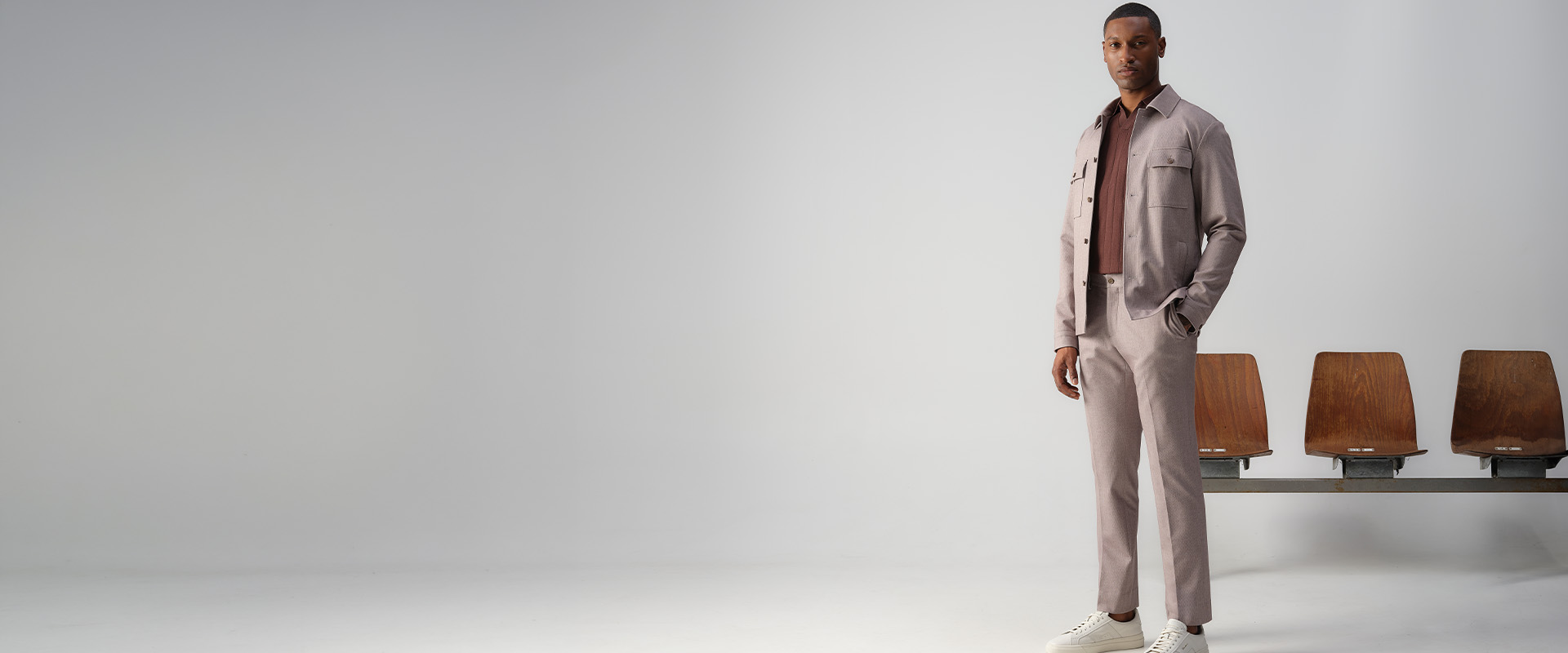 Man in een chino en overshirt van het merk Vesper die poseert voor gymstoeltjes