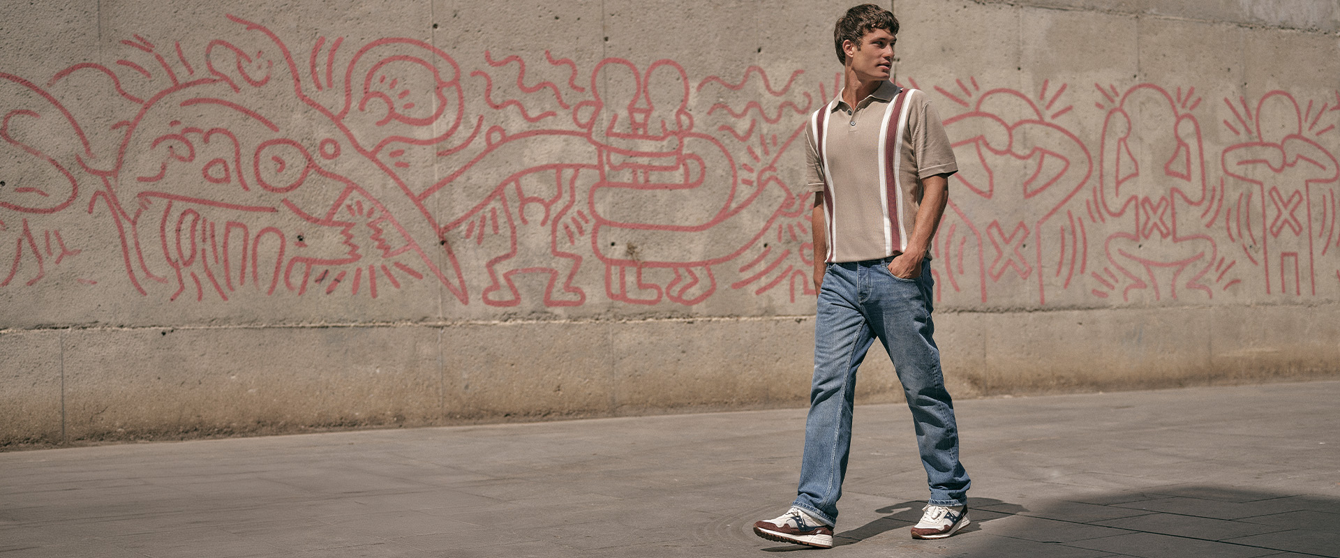 man lopend voor een met graffiti bespoten muur