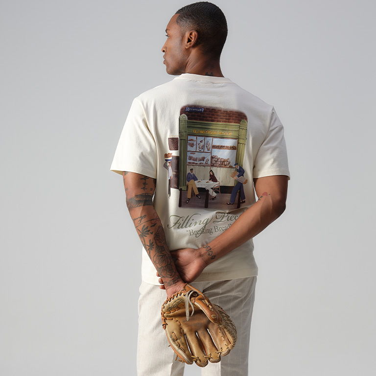 Man een tshirt aan met backprint en een honkbal handschoen aan.