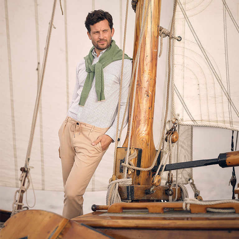 man leunend tegen een vlaggenmast op een zeilboot