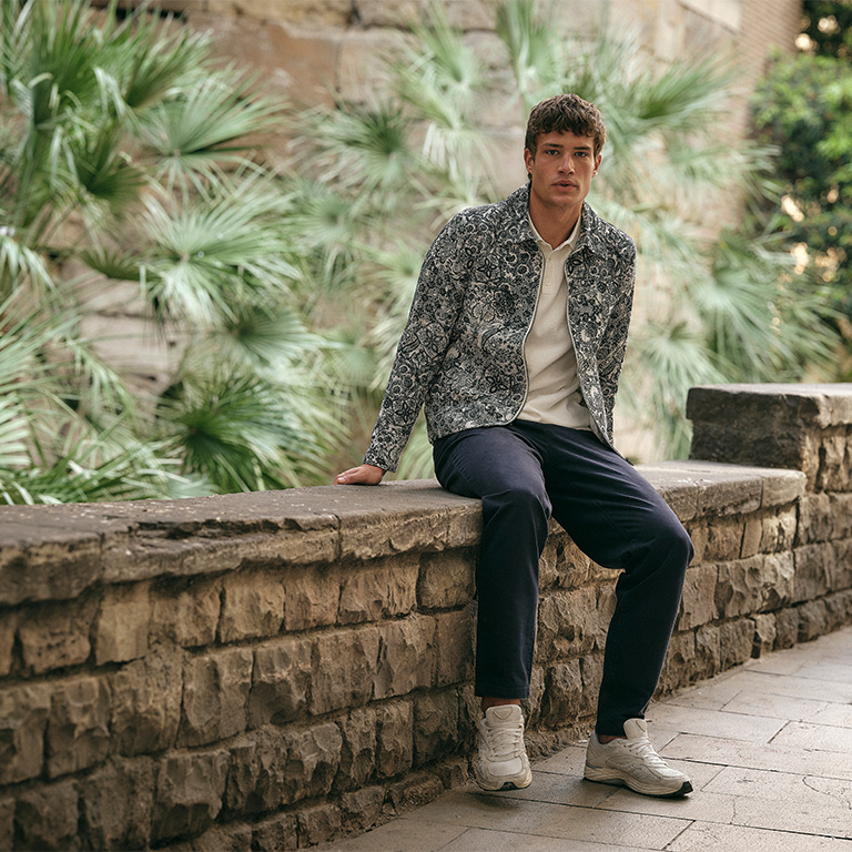 Man gekleed in kleding van het met jc rags zittend op een muurtje