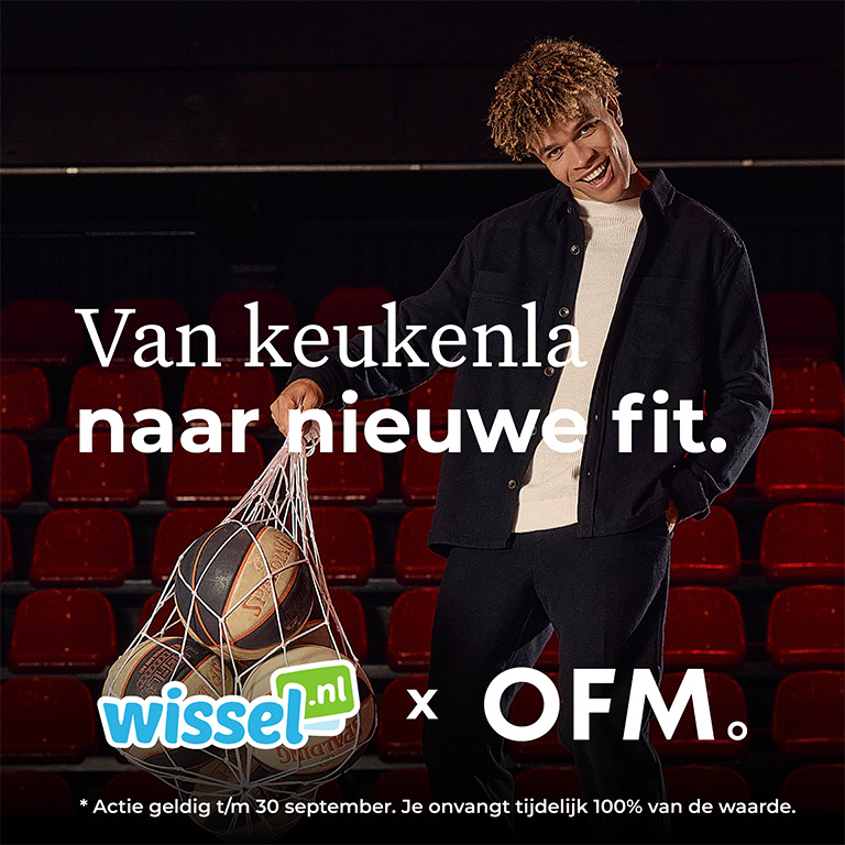 A person standing in a theater holding a net full of basketballs. Text in Dutch is displayed over the image.