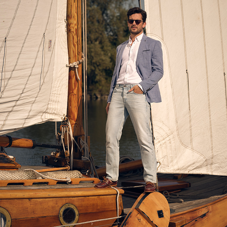 Man op een zeilboot leunend tegen de mast