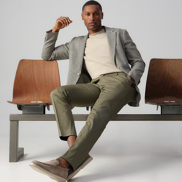 Man zittend op een stoel met een colbert en chino aan