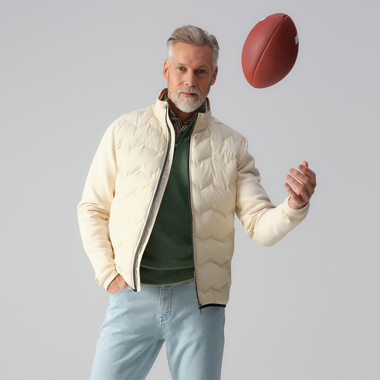 Model met een wit vest op een spijkerbroek en een bal in zijn hand