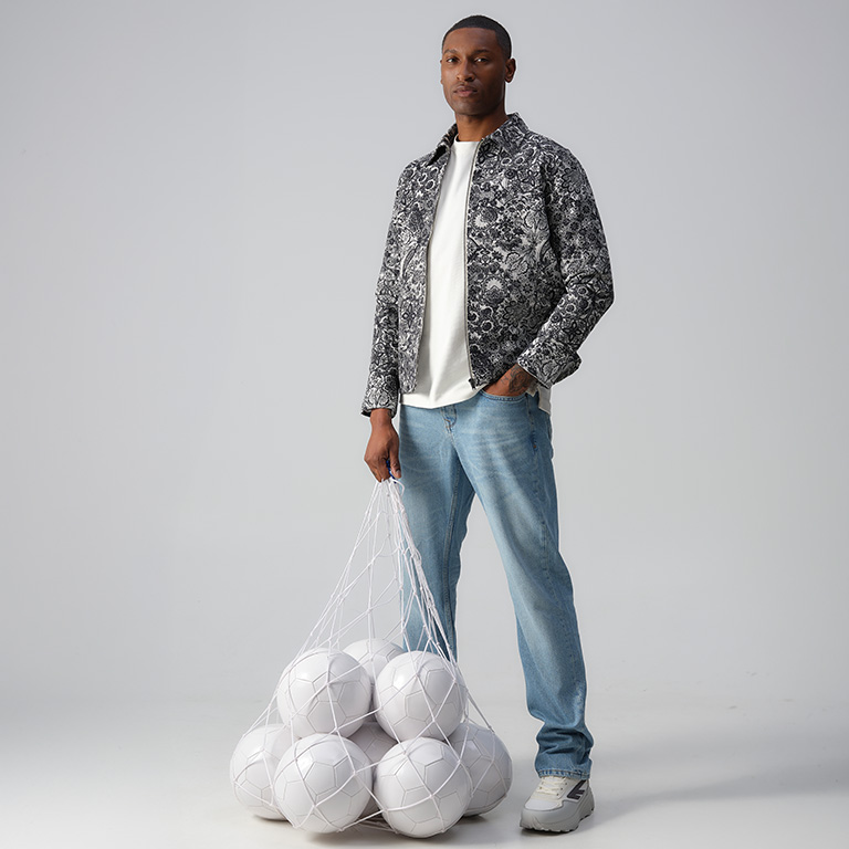 model met een zwart-wit gebloemd overshirt voor een zak met witte voetbal-ballen.