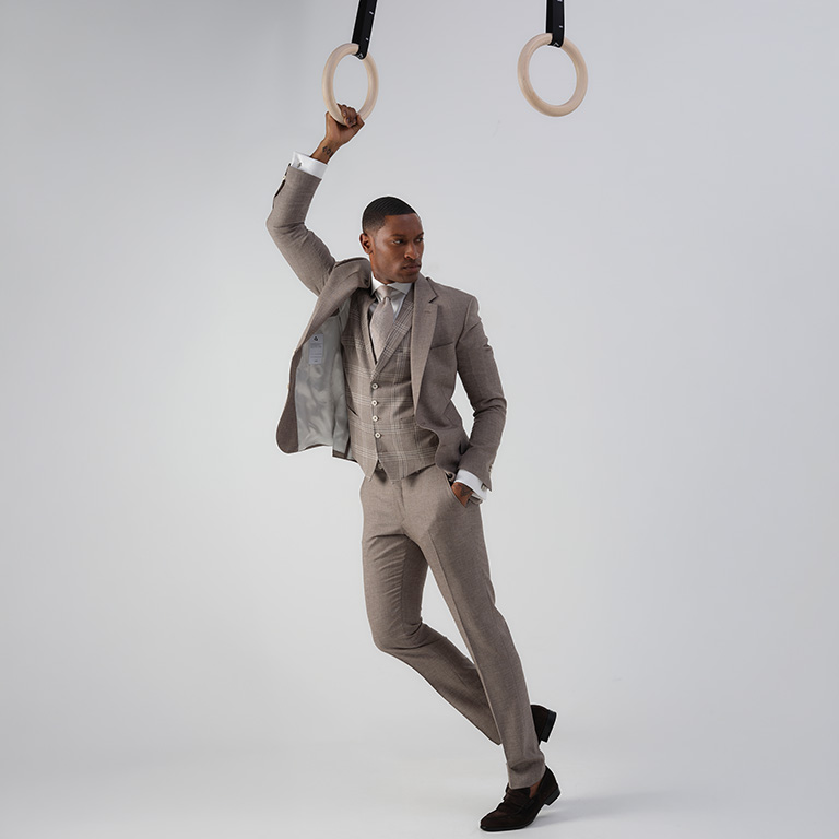 Man gekleed in drie-delig pak hangend aan turn-ringen