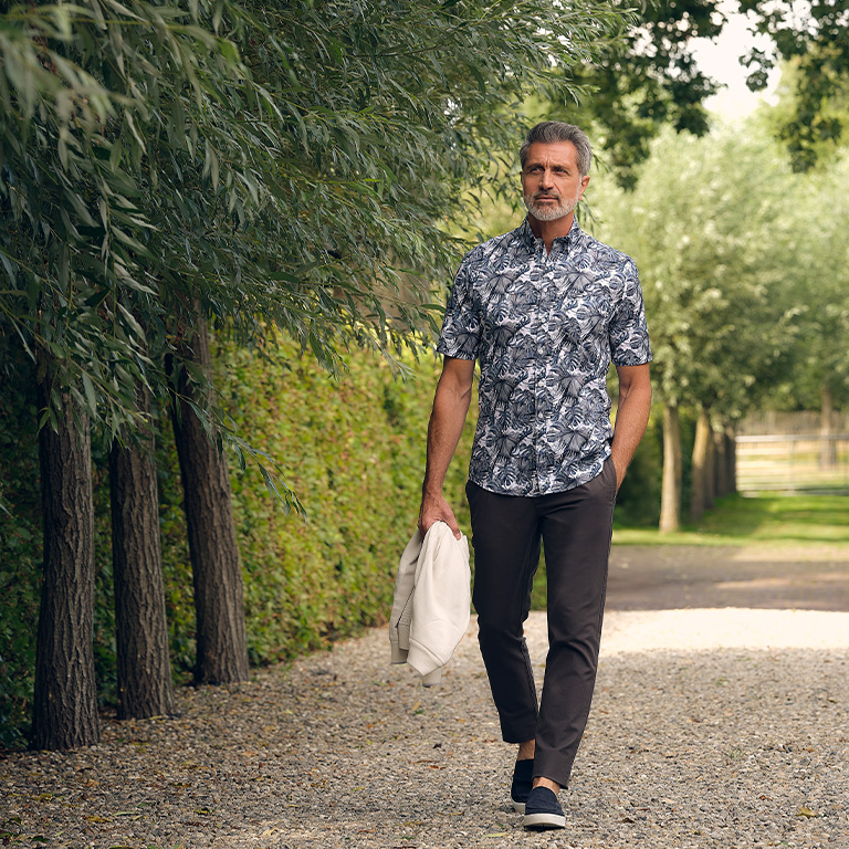 man die loopt over een grindpad langs bomen