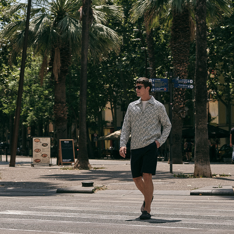 man lopend over een zebrapad met een overshirt en korte broek aan