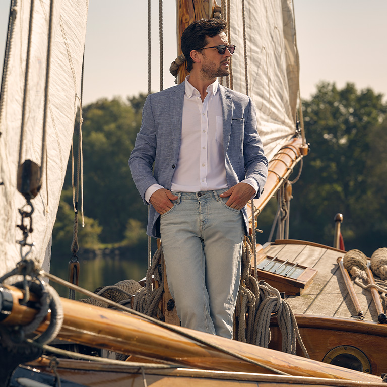 man poserend tegen vlaggenmast op zeilboot