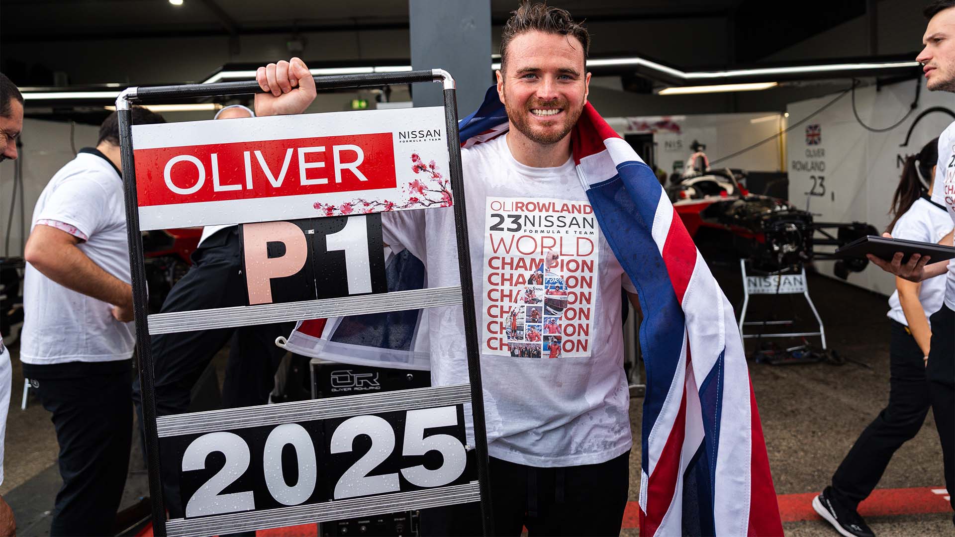 Oliver Rowland celebrates his world title with a pit board that reads 'Oliver P1 2025'