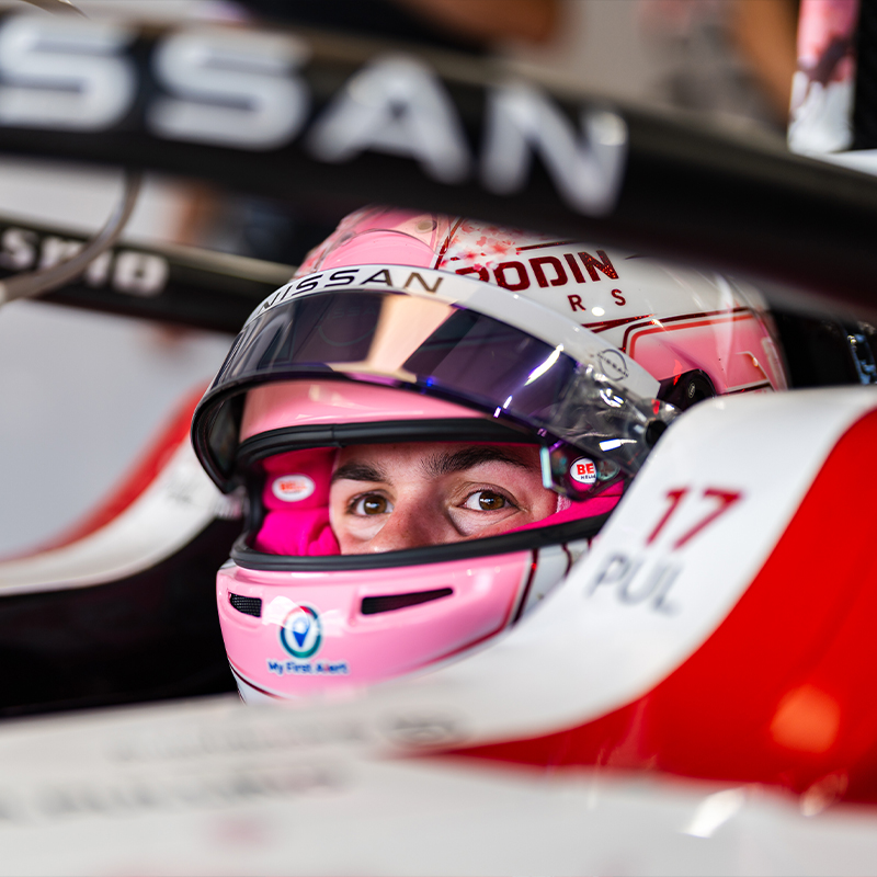 Abbi Pulling sits in the Nissan e-4ORCE 05 in the Nissan garage. She is wearing her pink helmet with the visor up