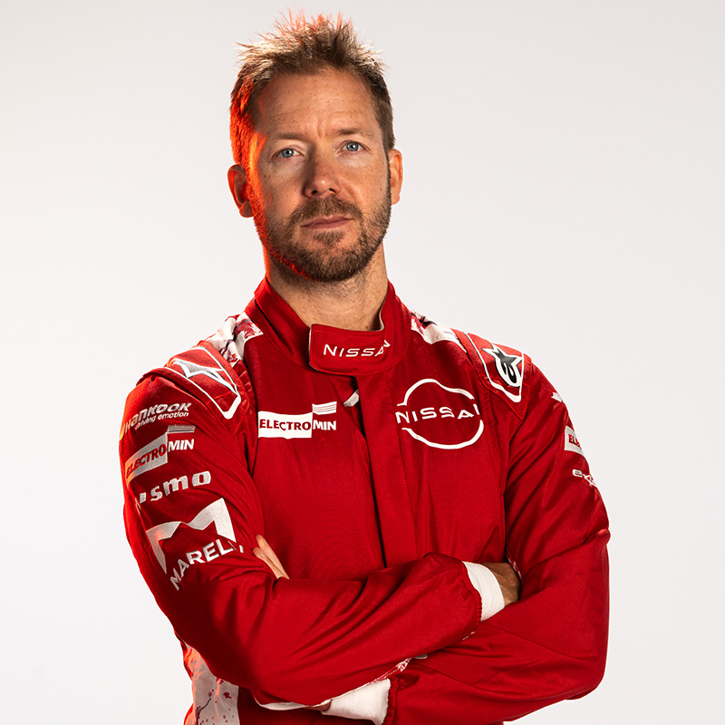 Sam Bird with arms folded, wearing his red Nissan Formula E Team race suit