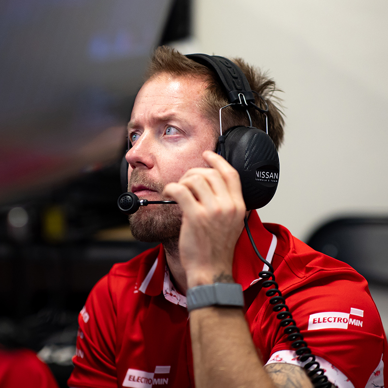 Sam Bird with headset on in the Nissan Formula E Team garage