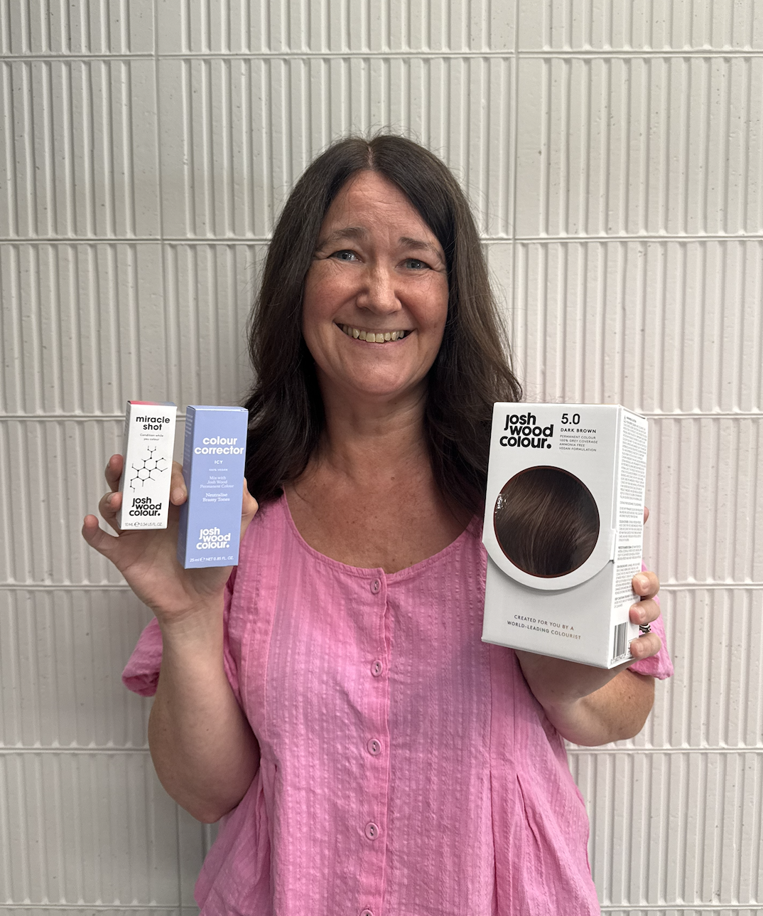 A lady with brunette hair holding Josh Wood Colour's Miracle System