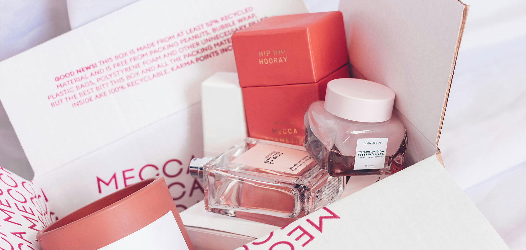 A box containing various skincare and cosmetic products in pink and red packaging, with visible brand labels.