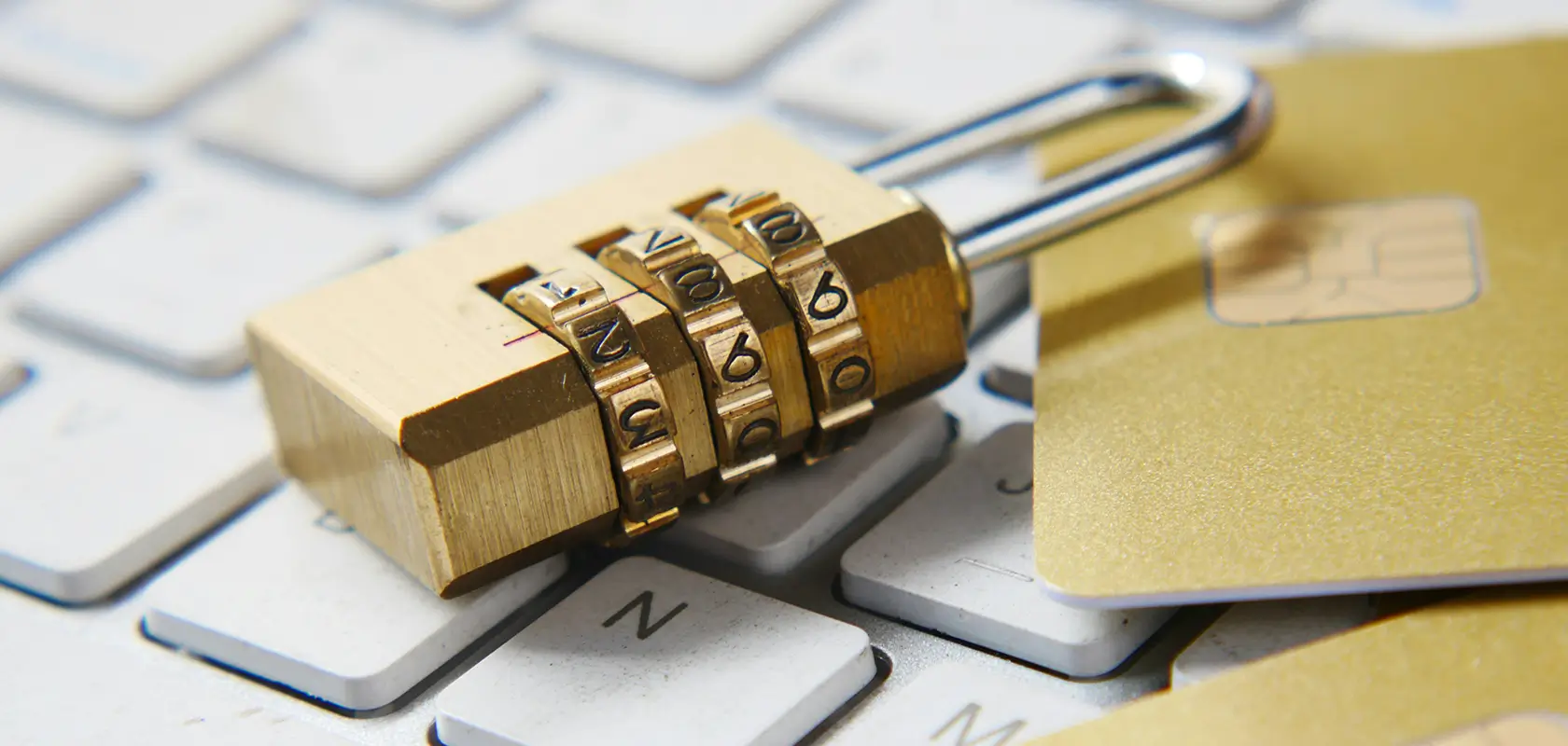 A combination lock and a credit card rest on a computer keyboard, symbolizing online security and data protection.