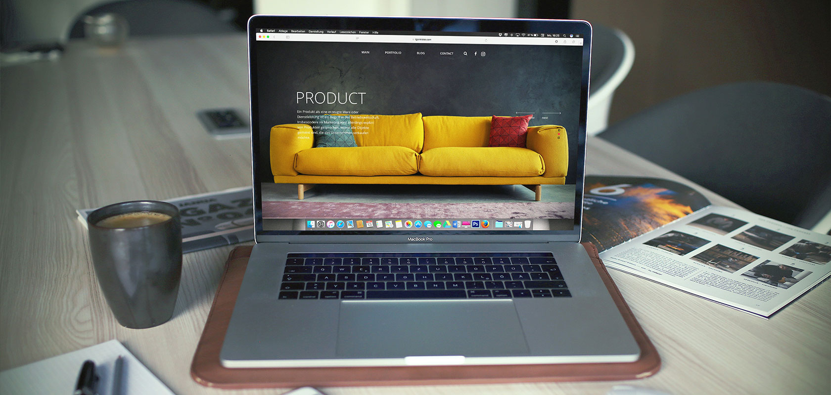 Laptop auf einem Tisch, auf dessen Bildschirm ein gelbes Sofa zu sehen ist, umgeben von Zeitschriften und einer Tasse Kaffee.