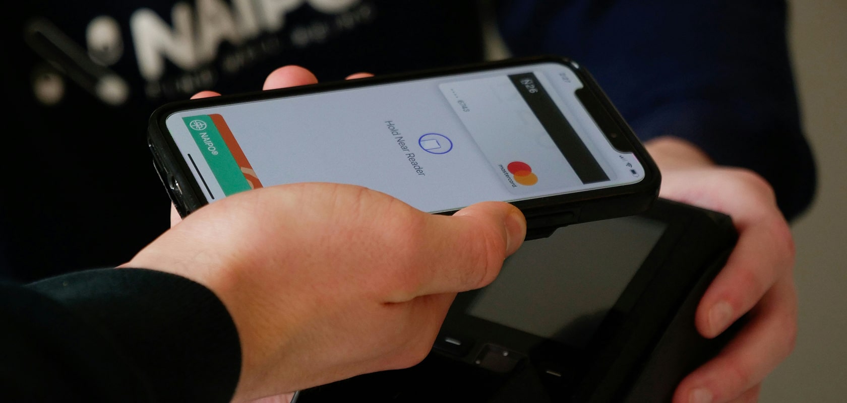 eine Person, die mit Apple Pay in einem Laden bezahlt