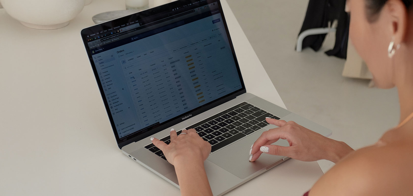 Person arbeitet an einem Laptop und betrachtet eine Bestellübersicht im Shopify-Adminbereich.