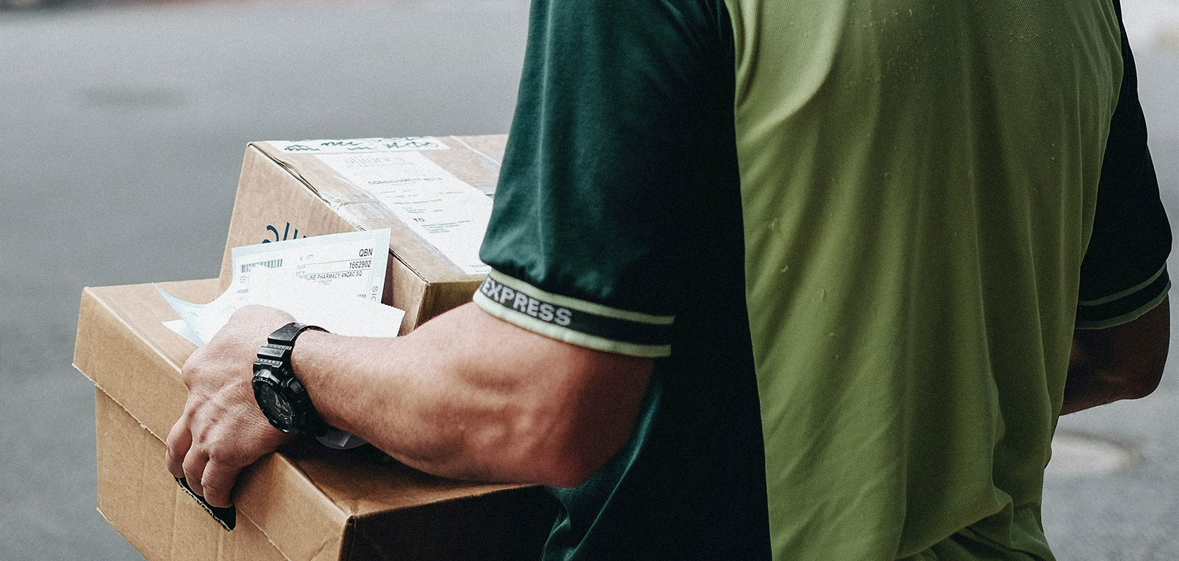 Paketzusteller trägt mehrere Kartons auf dem Arm.