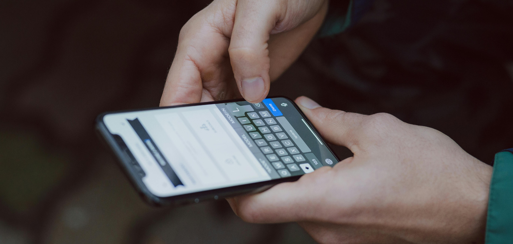 Hände, die eine Nachricht auf einem Smartphone tippen, mit geöffneter Tastatur und einem teilweise sichtbaren Chat-Bildschirm.